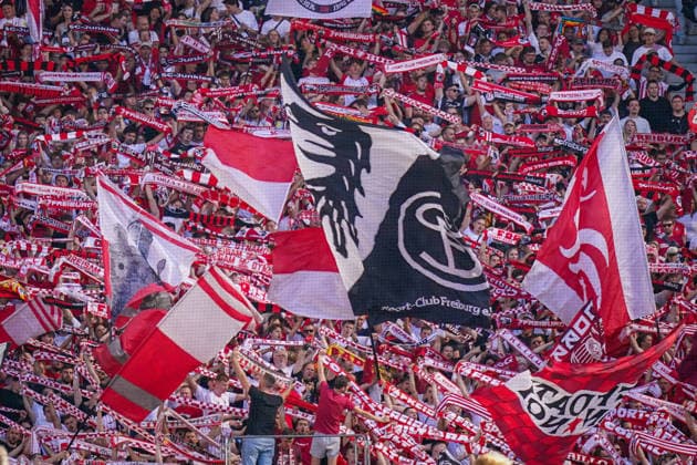 Deutschland: Fussball Bundesliga 2026 - 2027, 3. Spieltag - SC Freiburg vs Borussia Mönchengladbach - Europa-Park-Stadion (Freiburg): Fans des SC Freiburg auf voll besetzter Tribüne halten rot-weiße Fanschals und schwenken große Vereinsfahnen mit SC-Freiburg-Wappen. Fans, Zuschauer, Fankurve, Heimfans, Ultras, Fahnenmeer, Fanschal, Support, Stimmung, Fankultur, SC Freiburg, Vereinslogo, Fußball, Bundesliga, Stadion, Tribüne. *** Germany Soccer Bundesliga 2026–2027, Matchday 3: SC Freiburg vs. Borussia Mönchengladbach at Europa-Park Stadium, Freiburg. SC Freiburg fans in a packed stands hold red-and-white scarves and wave large club flags bearing the SC Freiburg crest. Fans, spectators, fan section, home fans, ultras, sea of flags, fan scarf, support, atmosphere, fan culture, SC Freiburg, club logo, soccer, Bundesliga, stadium, stands Copyright: xJOERANxSTEINSIEKx