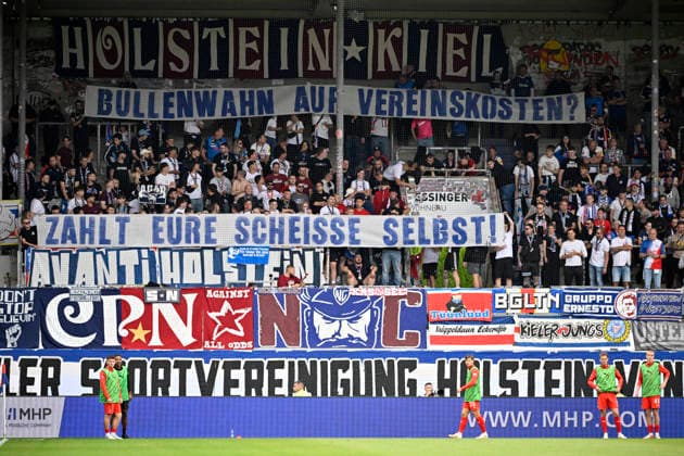 Fan section, fans, fan stands, flags, banners, atmosphere, atmospheric banner, protest, protest sign, fan sign, banner, poster, Banner protesting the allocation of costs for police operations 1 FC Heidenheim 1846 FCH vs. Holstein Kiel KSV September 13, 2026 DFL REGULATIONS PROHIBIT ANY USE OF PHOTOGRAPHS AS IMAGE SEQUENCES AND OR QUASI-VIDEO 1 FC Heidenheim 1846 (FCH) vs. Holstein Kiel (KSV)