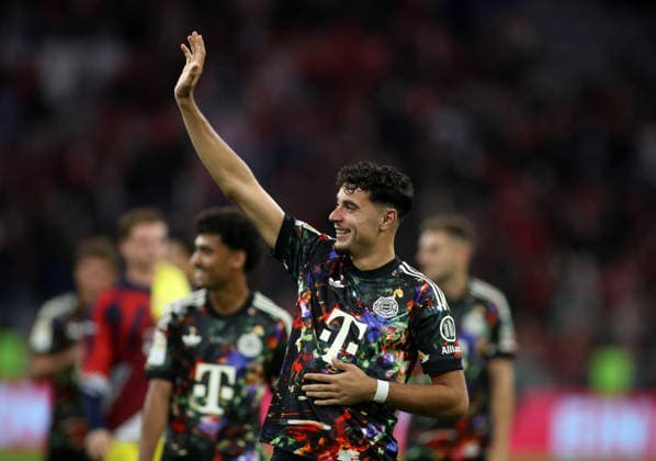 Soccer, Men s, Bundesliga, 2026–2027 Season, FC Bayern Munich vs. 1. FC Union Berlin, Allianz Arena: Aleksandar Pavlovic of FC Bayern Munich raises his right arm, waving and greeting. DFB and DFL regulations prohibit any use of photographs as image sequences and or quasi-video.
