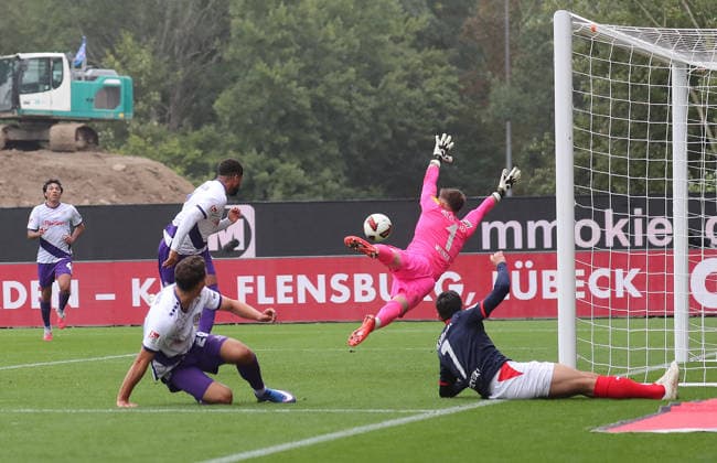 Daniel Kofi Kyereh of VfL Osnabrück is stopped by goalkeeper Timon Weiner, Holstein Kiel. Soccer, Men s, 2026–2027 Season, 2. Bundesliga, Holstein Stadium, Holstein Kiel vs. VfL Osnabrück, 1–1. DFL regulations prohibit any use of photographs as image sequences and or quasi-video.
