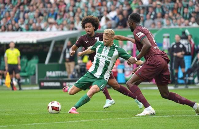 Photo by Marco GRÜLL: Werder taking a shot on goal against Han Noah MASSENGO (Augsburg) and Chrislain Matsima (Augsburg). Soccer, Bundesliga 1, Matchday 30, Sat, Apr 18, 2026. Werder Bremen vs. Hamburger SV