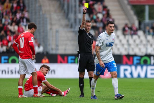 Soccer, 3rd Division, Matchday 7: Rot Weiss Essen vs. Hansa Rostock on September 20, 2026, at the Stadion an der Hafenstraße in Essen. Referee: Lukas Benen (Nordhorn), on the left is Niklas Kölle of Rostock; on the right is the yellow card. DFB regulations prohibit any use of photographs as image sequences and or quasi-video xJRx