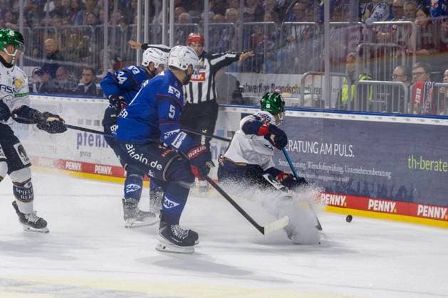Adam Smith (4, Berlin) kann den Puck erfolgreich abschirmen