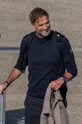 The German DFB national soccer team departs for Amsterdam for the Nations League match against the Netherlands, Nuremberg, September 23, 2026: National team coach Jürgen Klopp smiles as the German national soccer team departs for Amsterdam. He is carrying a backpack and has a jacket with the DFB logo draped over his arm, standing next to a suitcase on the tarmac in Nuremberg, Bavaria, Germany 20260923-1V9A8824-M4000