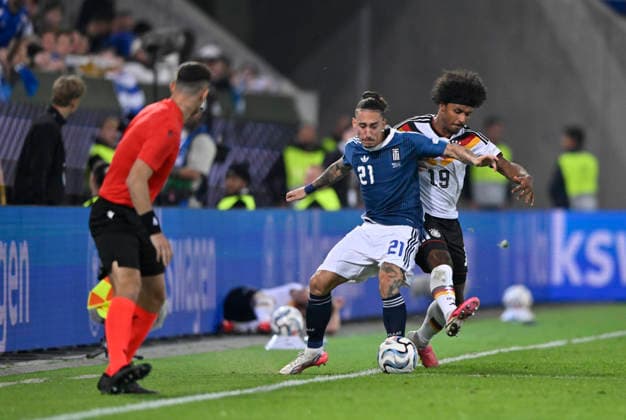 Tackle, Action: Karim Adeyemi (GER, 19) vs. Kostas Tsimikas (GRE, 21). Linesman Assistant Referee. DFB International Match: Germany (GER) vs. Greece (GRE), UEFA Nations League, September 27, 2026. DFL regulations prohibit any use of photographs as IMAGE SEQUENCES AND OR QUASI-VIDEO. DFB international match: Germany (GER) vs. Greece (GRE), UEFA Nations League