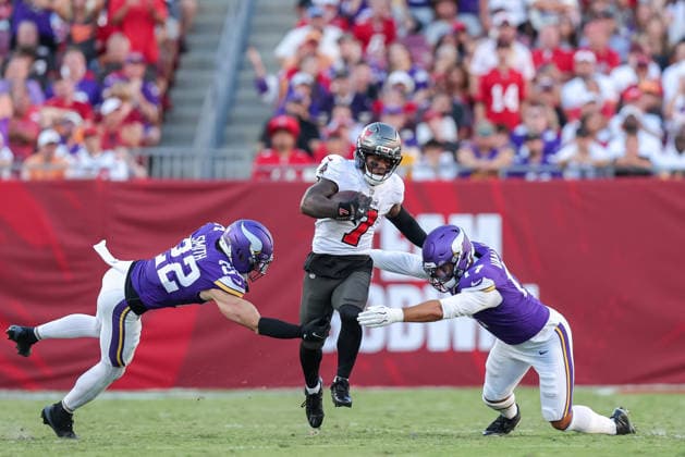 Sep 27, 2026; Tampa, FL, USA; Tampa Bay Buccaneers running back Bucky Irving (7) runs the ball through two Minnesota Vikings defensive players during an NFL, American Football Herren, USA football game between the Minnesota Vikings and Tampa Bay Buccaneers at Raymond James Stadium in Tampa, Florida. The Vikings defeated the Buccaneers 23-16. Mandatory Credit: Taylor McFee-Cal Media Tampa USA - ZUMAc04_ 20260927_zma_c04_099 Copyright: xTaylorxMcfeex