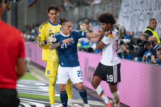 GER, Bavaria, Augsburg, Soccer, Germany vs. Greece, at the WWK Arena, Augsburg, UEFA Nations League, Matchday 2, Group Stage, September 27, 2026, from left: Kostas Tzolakis (Greece), 12, Kostas Tsimikas (Greece), 21, Karim Adeyemi (Germany), 19, tackle into the boards, foul, tackle, altercation, scuffle, physical confrontation, heckling, jersey pulling, unsportsmanlike conduct. DFL and DFB regulations prohibit any use of photographs as image sequences and or quasi-video, Copyright: HMB-Media MichaelxNibel