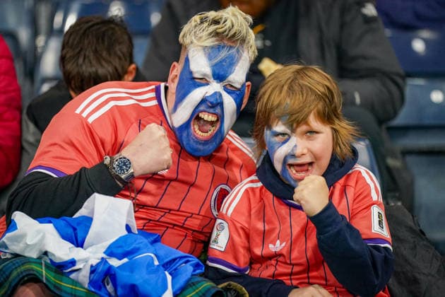 Soccer: UEFA Nations League 2026–2027, Matchday 2: Scotland vs. Switzerland at Hampden Park, Glasgow. Scottish fans at Hampden Park during the Scotland vs. Switzerland match. A man and a boy are wearing Scotland jerseys and have their faces painted in the colors of the Scottish flag. Both are cheering with clenched fists. Soccer, UEFA Nations League, Scotland, Switzerland, Fans, Spectators, Fan Culture, Father and Son, Face Painting, Saltire, Scottish Flag, Cheering, Emotions, Stands, Hampden Park, Glasgow Copyright: xJOERANxSTEINSIEKx