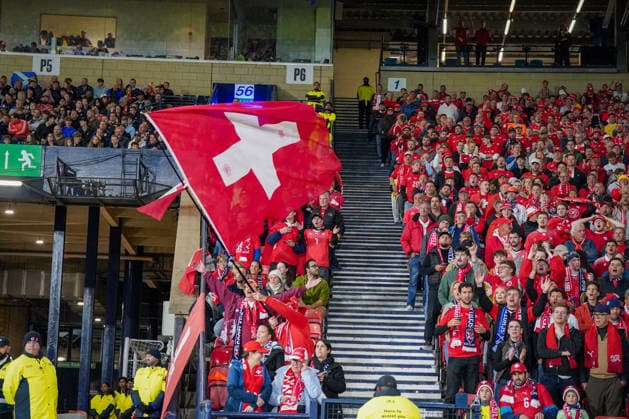 Soccer: UEFA Nations League 2026–2027, Matchday 2: Scotland vs. Switzerland at Hampden Park, Glasgow. Swiss fans in the stands at Hampden Park during the UEFA Nations League match between Scotland and Switzerland. A large Swiss flag is waved in the packed away section, and numerous fans are wearing red national jerseys and scarves. Soccer, Switzerland, fans, spectators, visiting fans, visiting section, stands, Swiss flag, national flag, fan culture, atmosphere, supporters, Hampden Park, Glasgow Copyright: xJOERANxSTEINSIEKx