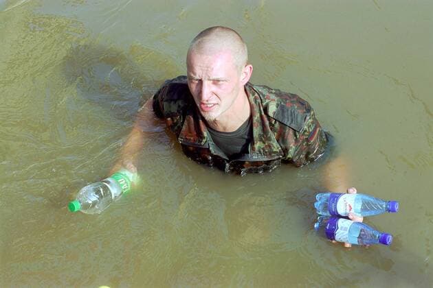 Bundeswehrsoldat steht mit Trinkwasserflaschen in der Hand bis zum Hals im Wasser
