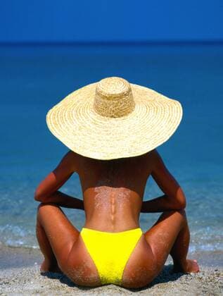 Junge Frau mit Sonnenhut schaut aufs Meer