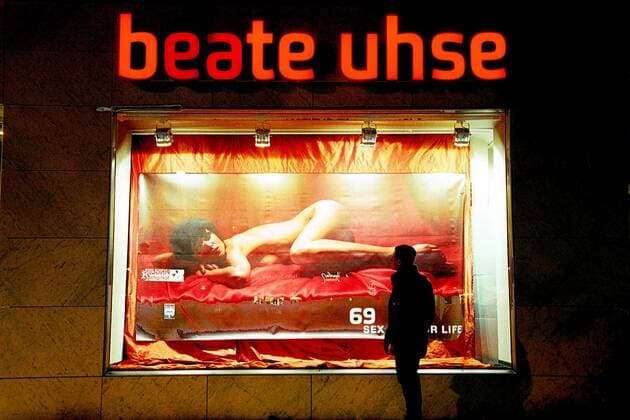 Mann bestaunt nackte Frau auf einem Beate Uhse Werbeplakat am Kurfürstendamm in Berlin