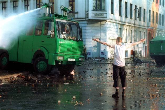 1. Mai-Krawalle am Mariannenplatz in Berlin-Kreuzberg - Demonstrant wartet die Wasserwerfer-Dusche der Polizei ab