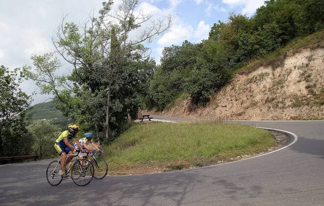Zwei sportliche Radfahrer erklimmen eine Bergstraße bei Gardone am Gardasee