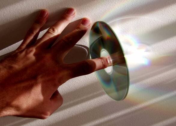 Hand hält eine CD-Rom auf dem Zeigefinger