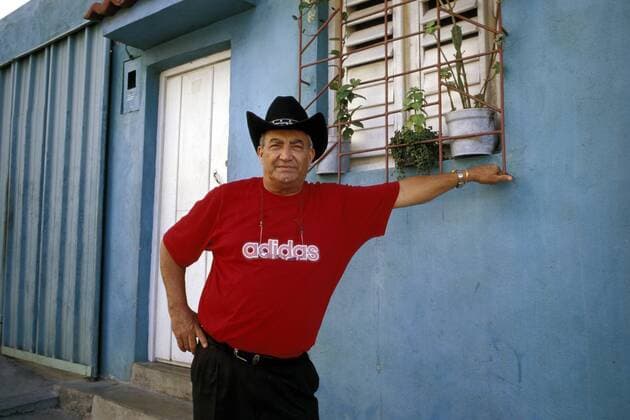 Sänger Eliades Ochoa (CUB) lehnt sich an ein blaues Wohnhaus in Santiago de Cuba
