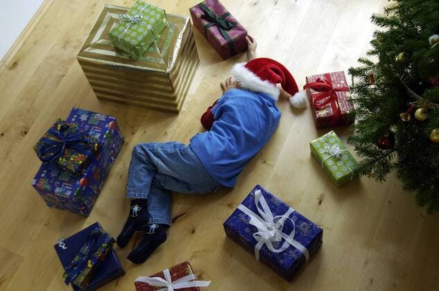 Junge liegt schlafend zwischen Weihnachtsgeschenken