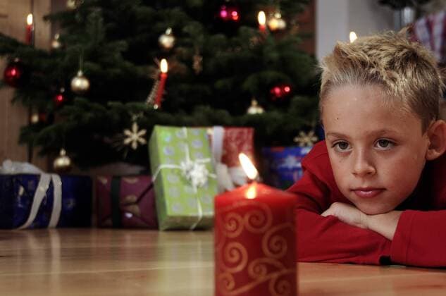 Junge schaut nachdenklich in eine Weihnachtskerze