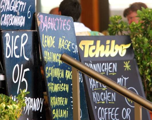 Werbeschilder eines Restaurants am Strand von Can Picafort auf Mallorca