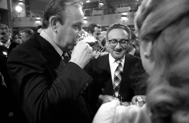 Henry Kissinger (Mitte, USA US Außenminister) lacht und Hans-Dietrich Genscher (li., GER FDP Bundesaußenminister) trinkt ein Glas Bier am Rande des Finales der Fußballweltmeisterschaft 1974 in München