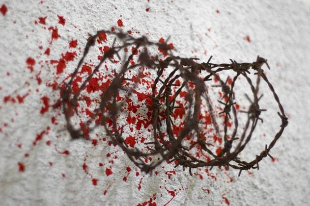 Stacheldraht liegt zusammengerollt auf blutbespritzten Untergrund