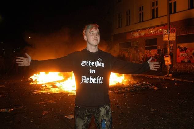 Scheißen ist Arbeit! - Punk steht mit ausgebreiteten Armen vor brennendem Müll - während der 1. Mai-Demonstrationen in Berlin-Kreuzberg