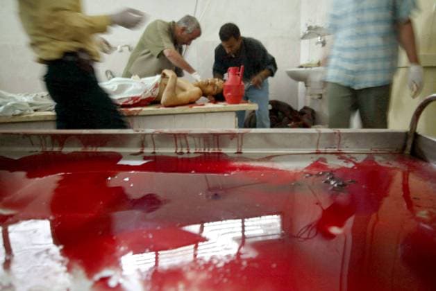 Ärzte untersuchen den Leichnam eines bei einem israelischen Angriff getöteten Palästinenser neben einer blutbeschmierten Liege im Leichenschauhaus im Flüchtlingslager Rafah im südlichen Gazastreifen  (gaz2005040906)