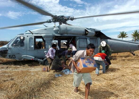 Einheimische und amerikanische Soldaten entladen einen Knighthawk-Helikopter der US-Armee während einer Hilfslieferung an die Opfer des Tsunamis auf Sumatra -  (wax20050119103)