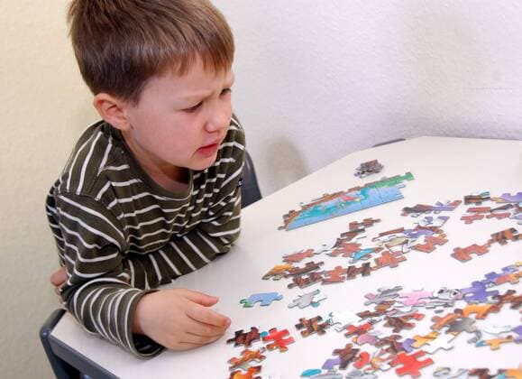 Kleiner Junge angestrengt beim Puzzeln