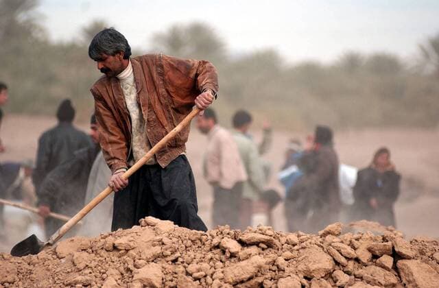 Einheimischer gräbt in den Trümmern seines von einem Erdbeben völlig zerstörten Wohnhauses in Bam im Iran nach Habseligkeiten -  (irn2003122712)