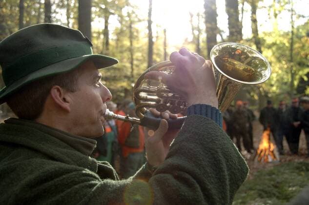 Jagdhornbläser bläst ins Horn während einer Hubertusjagd bei Binenwalde in Brandenburg