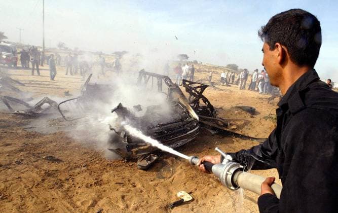 Palästinensischer Feuerwehrmann löscht ein Autowrack, das von der israelischen Armee beschossen wurde - Gaza Stadt -  (gaz2004030304)
