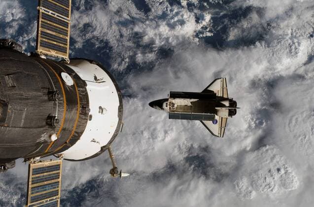 Space Shuttle Atlantis während der Mission STS-117 neben der angedockten Raumkapsel Sojus-TMA 9 im Weltall -  (wax200705627701)