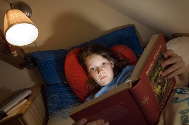 Mädchen liest im Bett ein Märchenbuch iblnmi00270298
