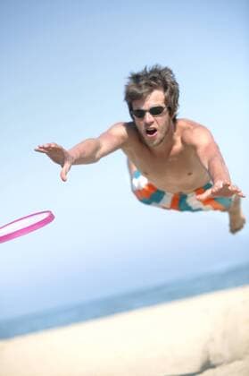 Junger Mann mit Sonnenbrille versucht einen Frisbee zu fangen