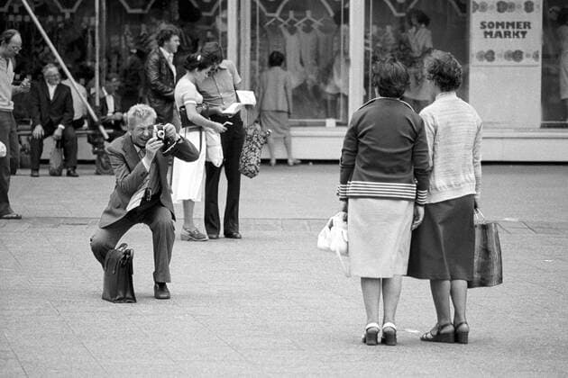 Touristen beim Fotografieren vor dem Centrum Warenhaus auf dem Alexanderplatz in Berlin Ost