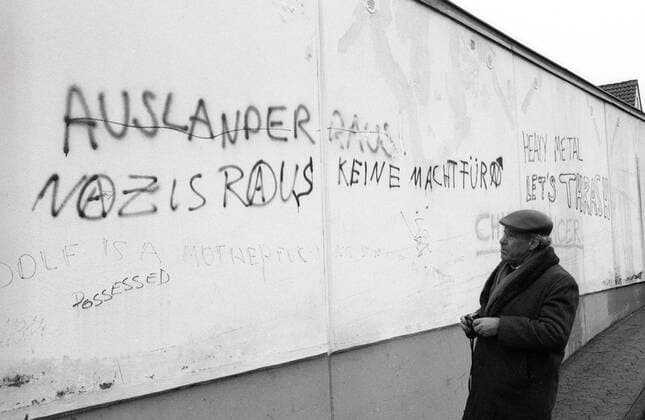 Autor Sally Perel (Hitlerjunge Salomon) neben einem Graffiti - Ausländer raus, Nazis raus -