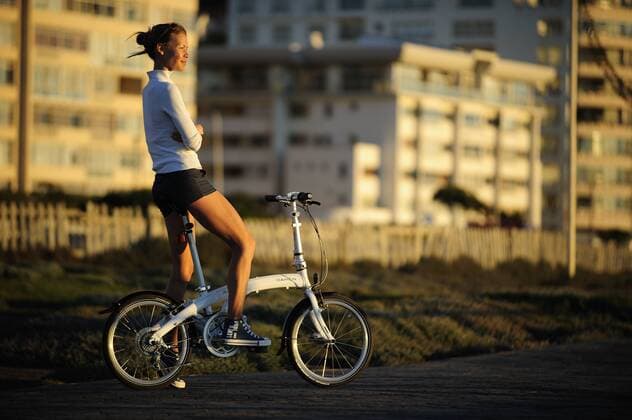 Junge Frau auf einem Klapprad am Mouille Point bei Kapstadt