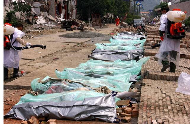 Medizinische Hilfskräfte sprühen Desinfektionsmittel auf zugedeckte Leichen nach dem Erdbeben in Beichuan, China - 
