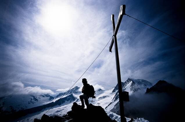 Bergsteigerin steht am Gipfelkreuz in den Zillertaler Alpen in Tirol (iblgzs00838600)