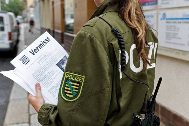 Polizistin verteilt Flugblätter mit Fotos des vermissten Mädchens Michelle in Leipzig