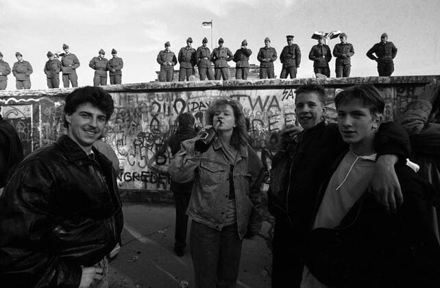Jugendliche feiern unter den Augen von Volksarmisten den Fall der Berliner Mauer