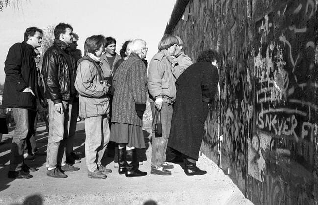 Neugierige Blicke durch die Berliner Mauer - Mauerfall in Berlin