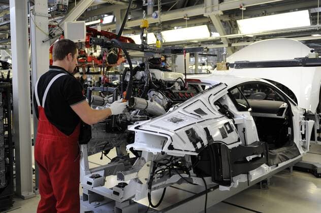 Arbeiter führt einen Motorblock - Motoreinbau bei der Fertigung des Audi R8 in der Manufaktur Audi Werk Neckarsulm