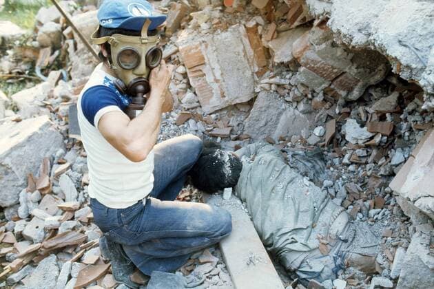Retter mit Gasmaske findet Leichnam eines Verschütteten nach dem schweren Erdbeben im Friaul - Italien