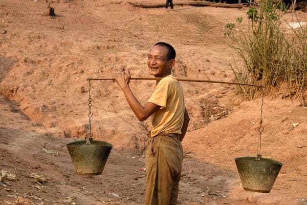 IMAGO Cultures of the world, Akha Volk in Laos Armut, Mann der Akha Djepia Ethnie trägt Wasser in Eimern, Dorf Ban Chakhamdaeng, bei Nam Lan Conservation Area, Distrikt Boun Tai, Provinz Phongsali, Phongsaly, Laos, Südostasien, Asien iblsau01265614