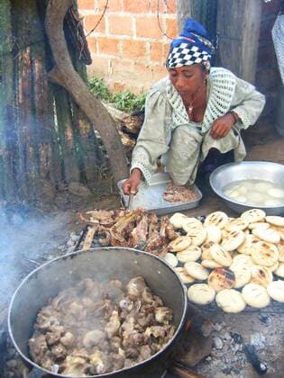 IMAGO Cultures of the world, Wayuu Volk in Kolumbien Wayuu Indianerin in traditioneller Kleidung kocht Lammfleisch und almohabanas auf der Halbinsel Guajira, Kolumbien, La Guajira Indian Wayuu woman in traditional clothing cooking lamb and almohabanas on the peninsula of Guajira, Colombia, La Guajira BLWS167534
