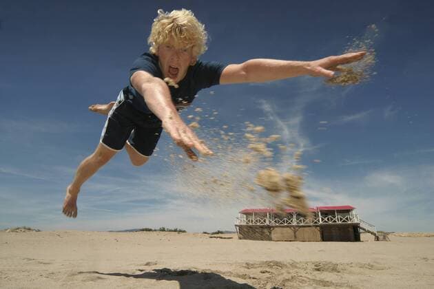 Junger blonder Mann am Strand springt nach Frisbeescheibe young fair-haired man jumping for a frisbee disk BLWS111435