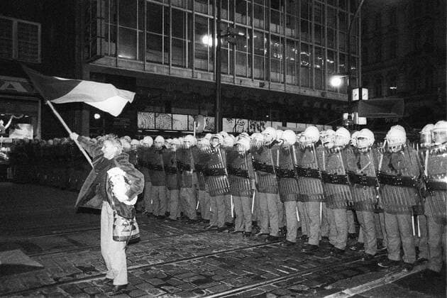 Velvet Revolution. Protester waves Czechoslovak flag in front of police cordon at Narodni Trida in Prague, Czechoslovakia on Nov. 17, 1989. The events of November 1989 started by brutally supressed student demonstration led to government fall and the end of communism regime in Czechoslovakia. 
