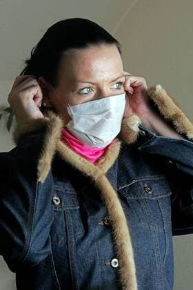 Junge Frau legt einen Mundschutz an. - MODEL RELEASED